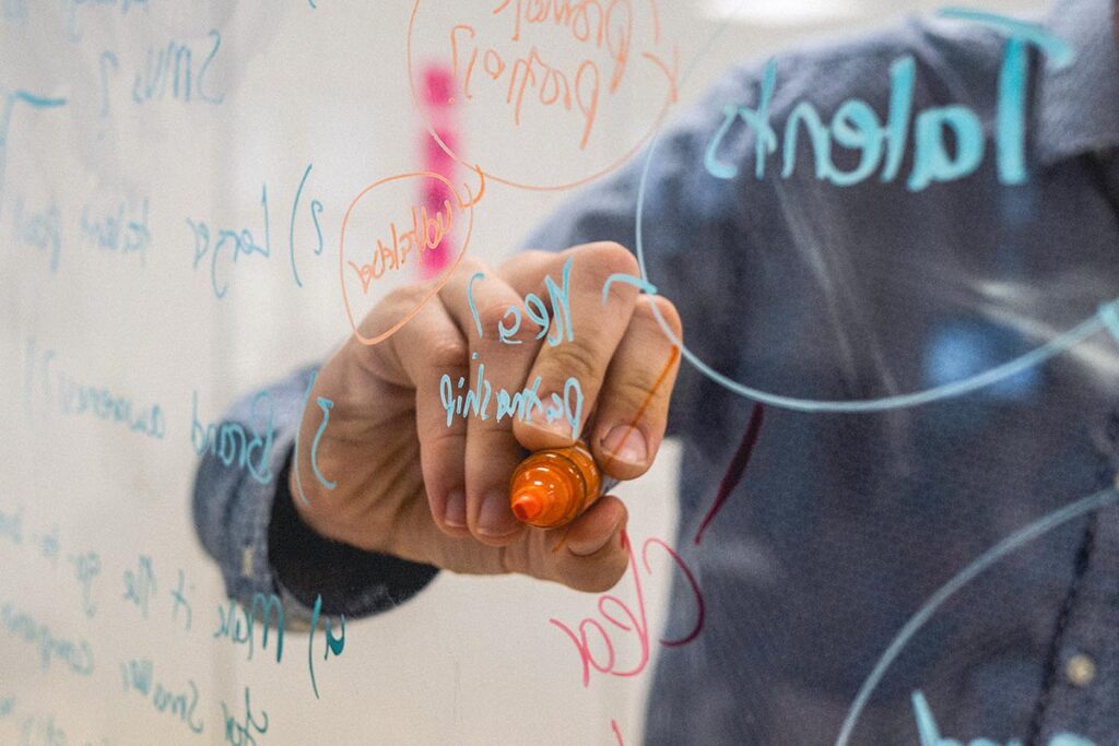 Hand schreibt auf transparentes Whiteboard